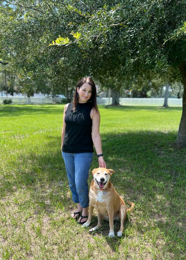 Agape Owner Trish Standing Next to a Dog and Smiling